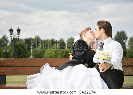 fiance and bride kiss on the bench