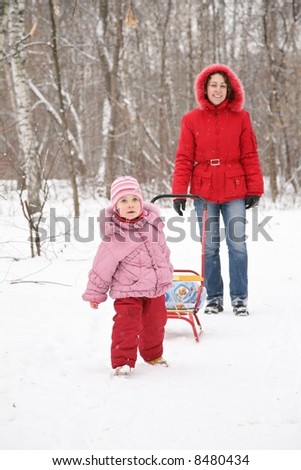 child with sled and mother in park at winter 2