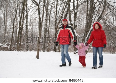 father and mother walk in park with child at winter
