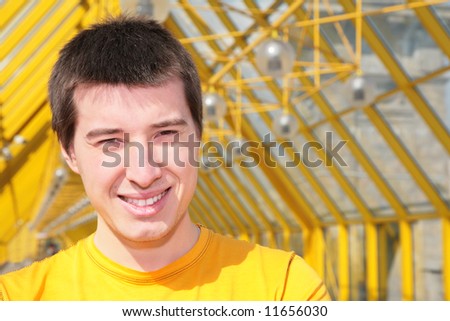 young smiling man in yellow shirt on footbridge