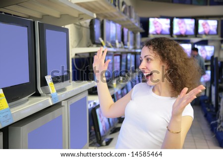 young woman in delight looks at TVs in shop