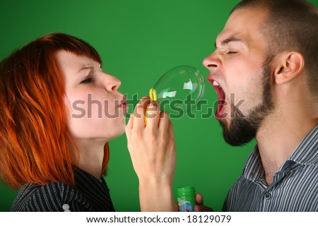 Girl with red hair blows soap bubble in mouth to guy