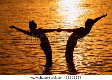 Pair keeps for hands in sea on sunset