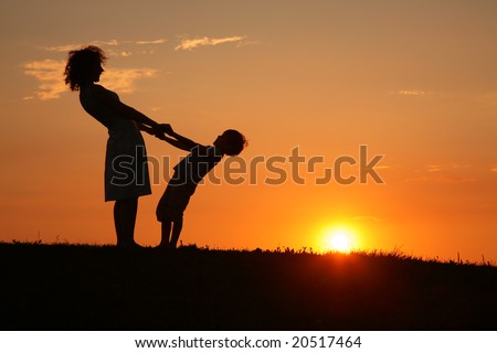 Mother and son on sunset holding by hands