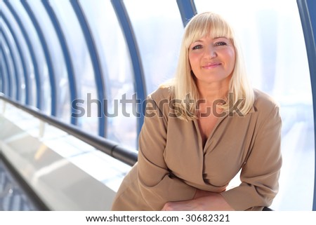 Happy middle-aged businesswoman near glass wall