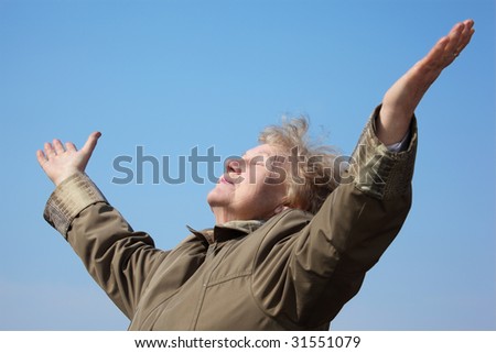 Elderly woman with rised hands on sky