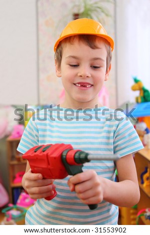 Boy in plastic helmet with toy drill