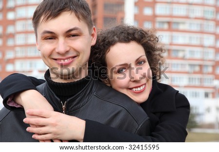 young pair embraces and smiles against building