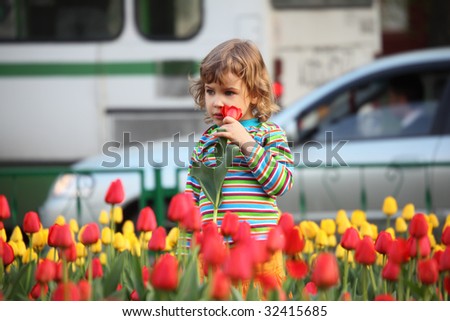 Little girl in striped t-shirt and tulips on street