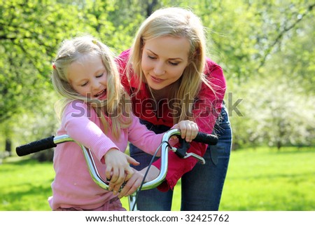 Mother with  daughter on bicycle in spring garden