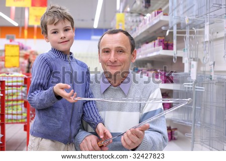 elderly man with boy in store with grill for roasting in hands, looking at camera