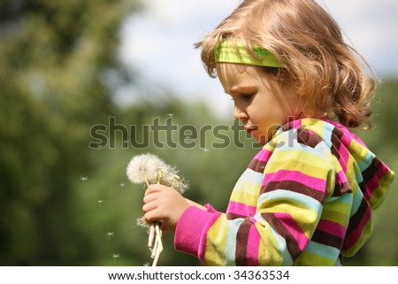 small thoughtful girl with dandelions in hand