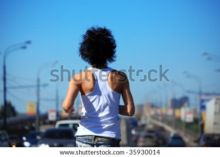 behind girl goes on road among cars,  rear view on belt