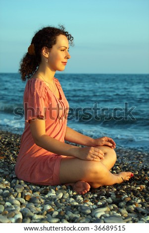 young woman sits and meditation ashore of sea