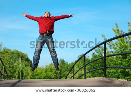 man in red shirt jumps outdoor in summer on bridge