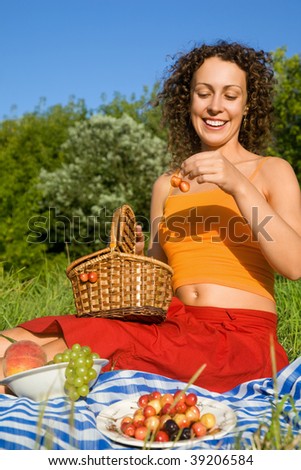 Young Women will get from basket sweet cherries in garden