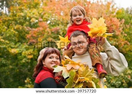 Married couple and little girl collect maple leafs In park in autumn