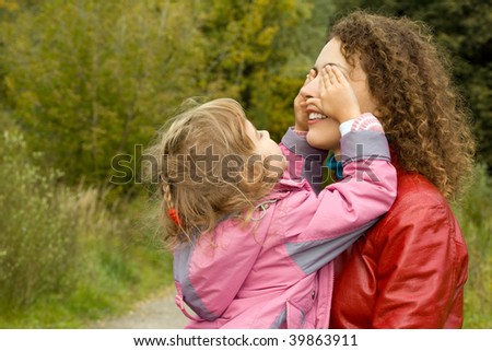 young woman and little girl playing in garden, girl closes eyes to mother
