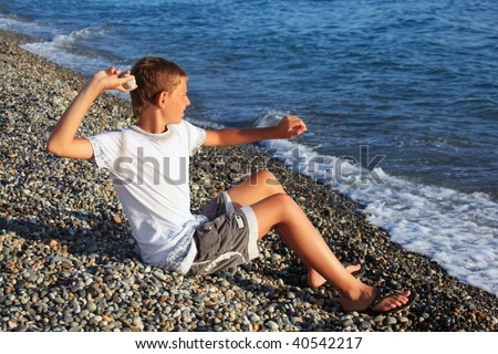 sitting boy throws stone in sea