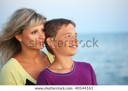 smiling boy and young woman on beach in evening, Looking afar