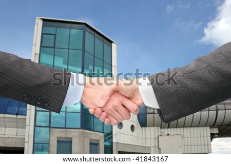 Wrists And Hands. stock photo : shaking hands with wrists near blue building