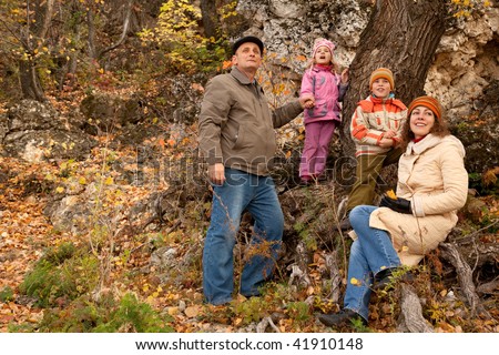 Mother, daughter, son and grandfather in autumnal forest near the tree