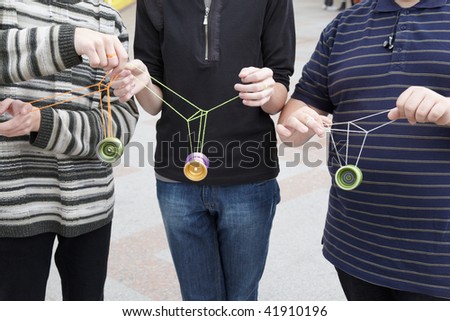 three teens with yo-yo toys in their hands. focus on yo-yo