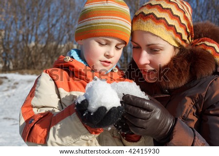 Mum with the son play with snow outdoor