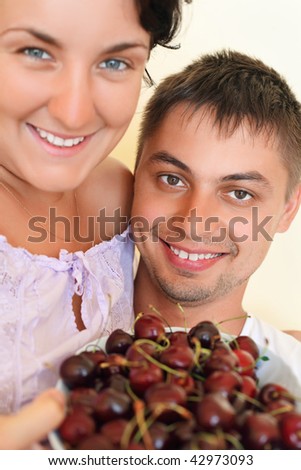 Smiling man and young woman eat cherries