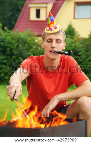 stock photo : young man with calumet near brazier on picnic, happy birthday party
