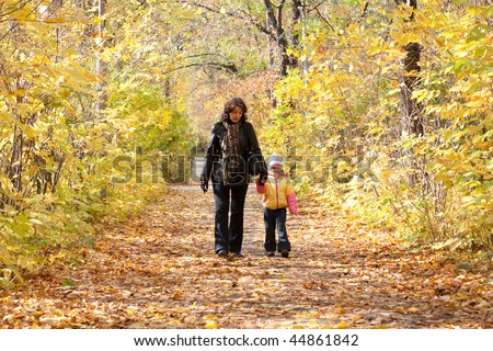 Mother and daughter walk on foot on autumnal park