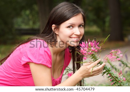 Portrait of smiling girl in summer garden. Girl near to flower, looks in camera.