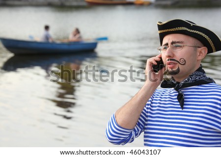 man in pirate suit is talking by the phone. boat in out of focus