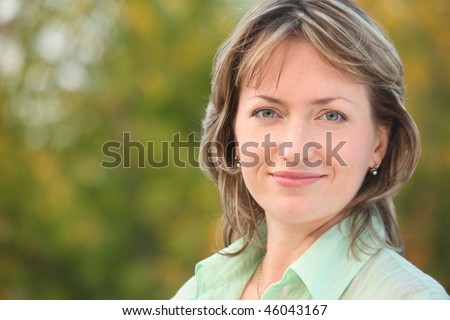 portrait of smiling woman in early fall park. she is looking at camera.