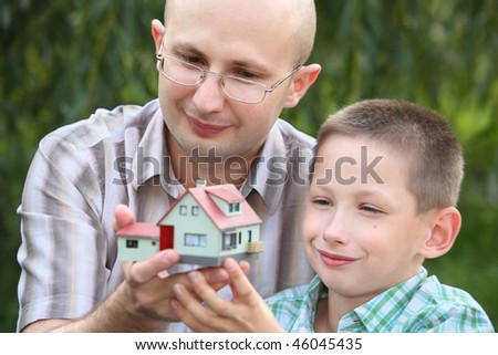father and son keeping in their hands wendy house. focus on father\'s face. wendy house in out of focus.