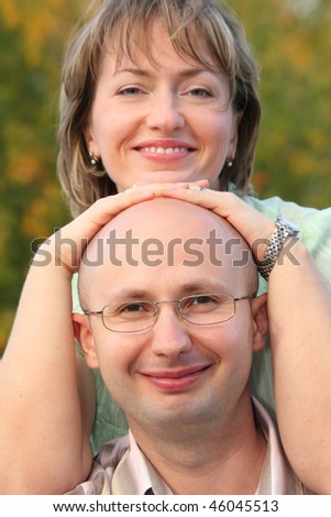 man and woman in early fall park. woman's hands on man's head