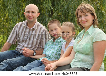 family with two children sitting at the grass in early fall park. focus on little girl\'s face