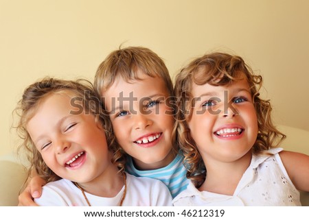 Smiling children three together in cozy, girl at left closed eyes