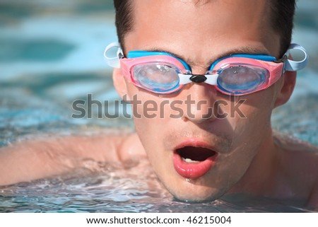 young man in waters sport goggles swimming in pool, taking breath