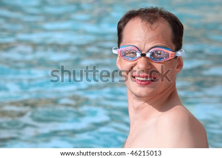 smiling young man in waters sport goggles swimming in pool