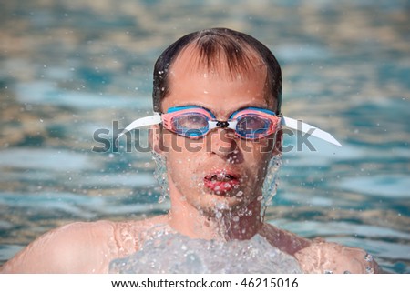 young man in waters sport goggles swimming in pool, come up from water