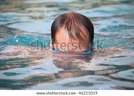 young man in waters sport goggles swimming in pool, dives under water