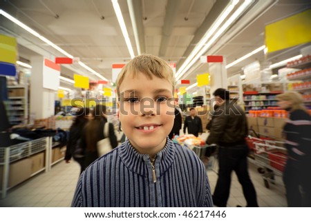 Smilling boy stand in center of trading floor in supermarket