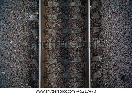 Rails and cross ties of railway among stones on center