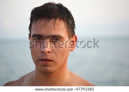 Portrait of man come up from water, on background of the sea and sky. Looks in camera.