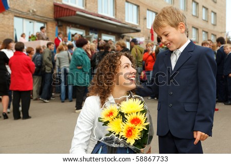 First class, a boy and his mother a bouquet of flowers stood at the entrance to the school.