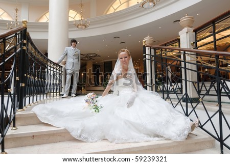 stock photo Bride in beautiful wedding dress sits on wide spiral staircase
