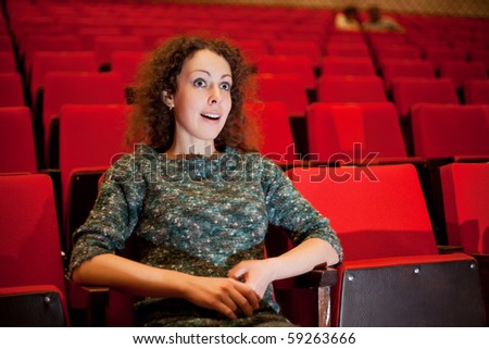 beautiful young woman sitting on armchairs at cinema, steadfastly looking