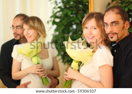 man in glasses and beauty blond girl with flowers bouquet standing near mirror and smiling
