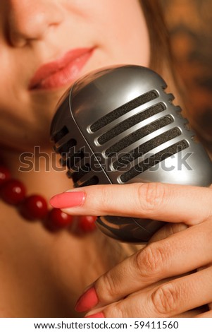 woman hugged hand vintage microphone placed on a rack. in the background lips. Focus on the microphone